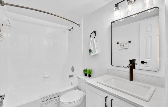 A white bathroom with a toilet, sink, and mirror.