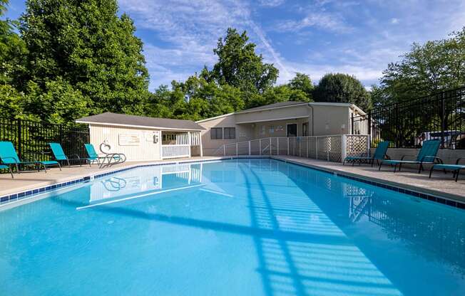 a swimming pool with chairs and a house in the background