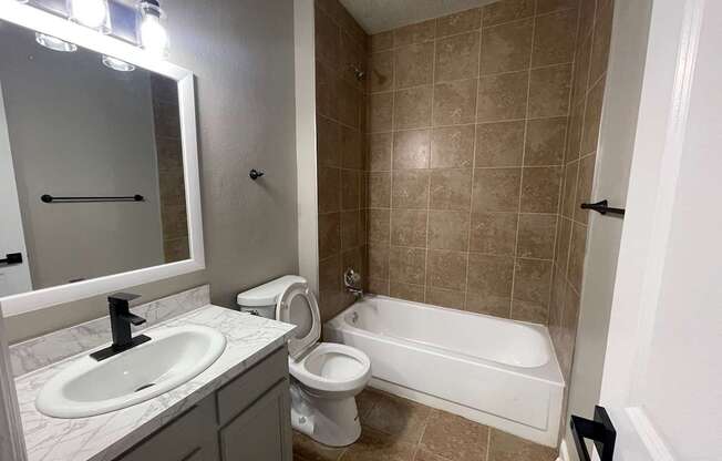 A bathroom with a sink, toilet, and bathtub.