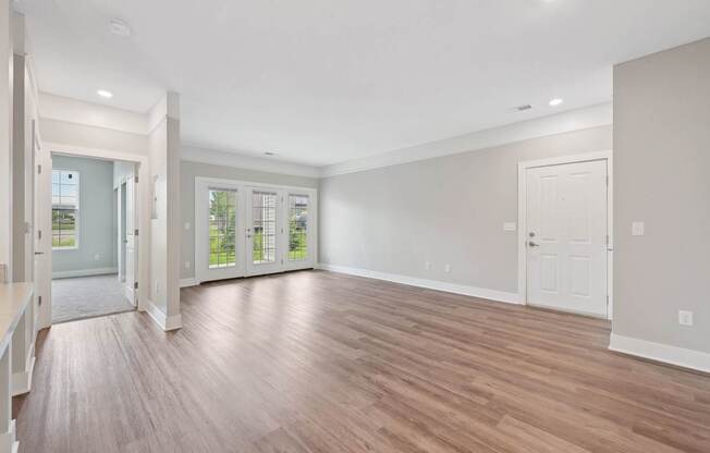 A spacious room with wooden flooring and white walls.