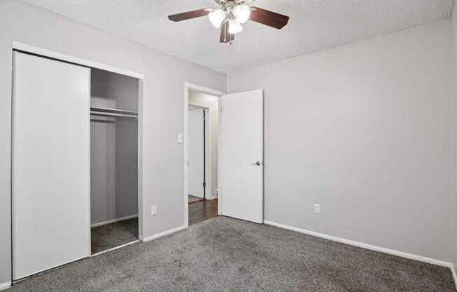 A room with a ceiling fan and carpeted floor.