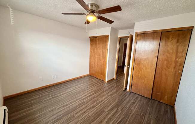 A room with a ceiling fan and wooden flooring.