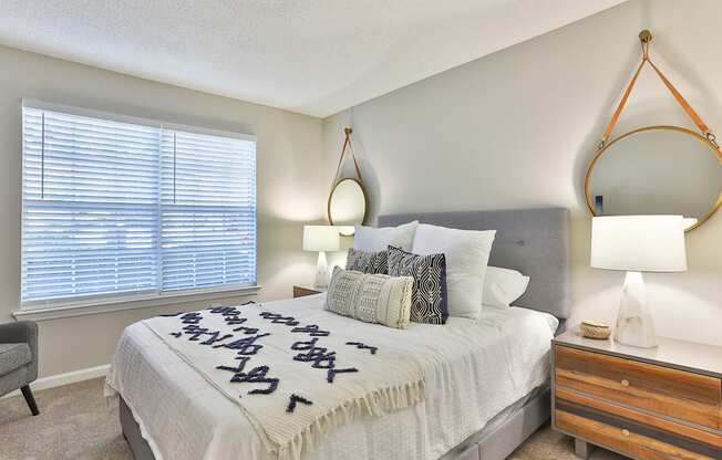 a bedroom with a large window and a large bed with a white comforter and pill