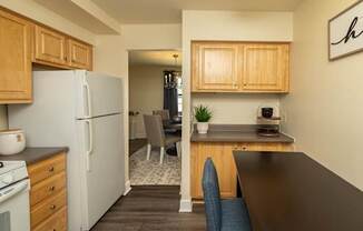 A kitchen with a refrigerator, stove, and wooden cabinets.
