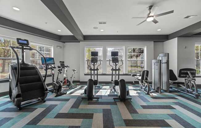 A gym with a variety of equipment including treadmills, stationary bikes, and weight machines.