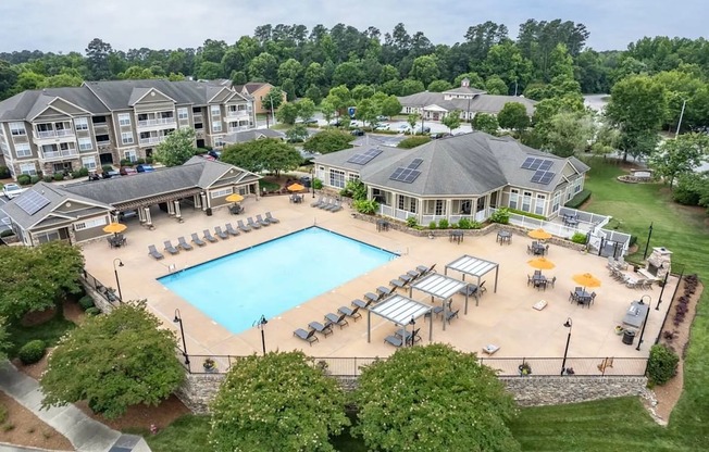 A large swimming pool surrounded by sun loungers and umbrellas in a resort-like setting.