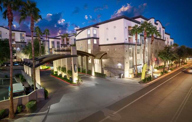 A modern building with a curved entrance and palm trees in front.