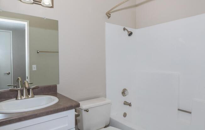 a white sink sitting under a mirror