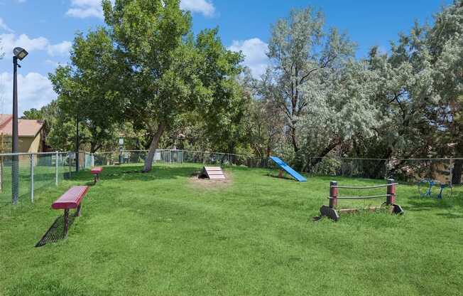 A park with a red bench, a blue slide, and a green lawn.