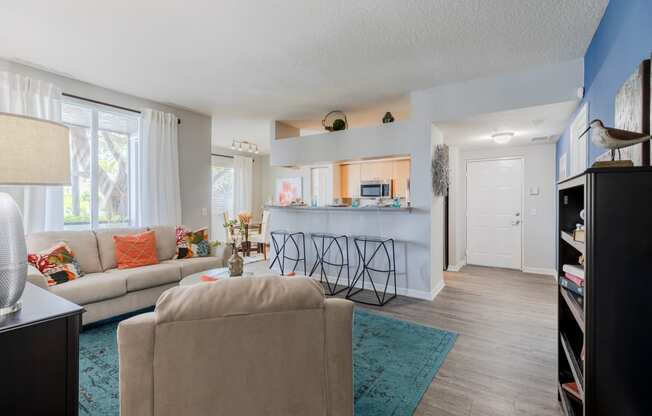 a living room with a kitchen in the background and a couch and chair in the foreground at Heritage Bay, Jensen Beach, FL 34957