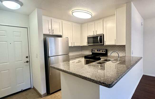 a kitchen with a granite counter top and a stainless steel refrigerator