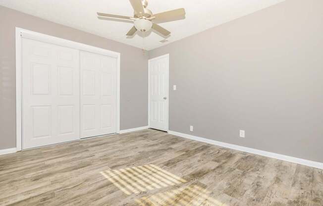 an empty room with a ceiling fan and a closet