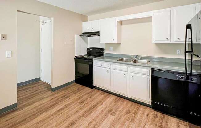 A kitchen with black appliances and white cabinets at The Hampton Meadows Apartments, Des Moines, IA, 50315