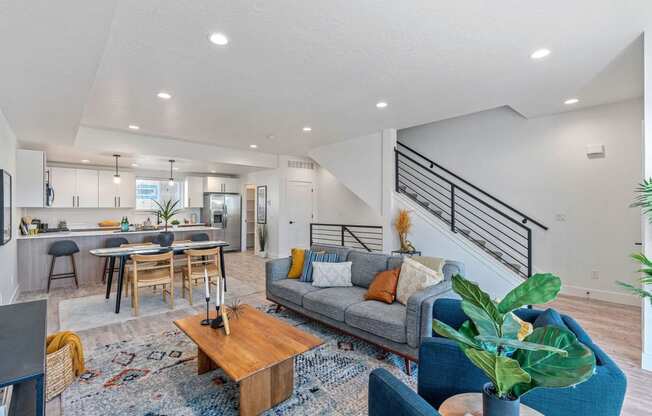 a living room with a couch and a kitchen with a staircase