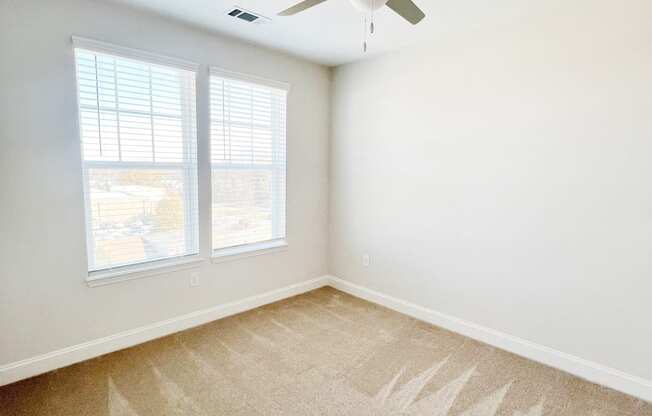 A room with a ceiling fan and carpeted floor.