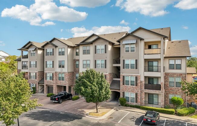 A large apartment complex with a parking lot in front.