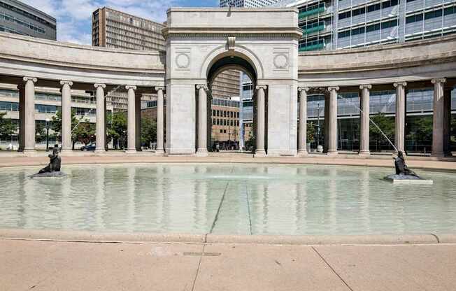 A fountain in front of a building with a large archway.