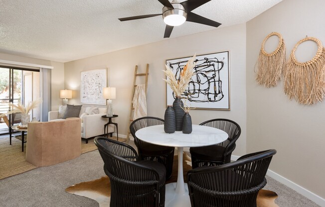 a dining area with a table and chairs and a ceiling fan