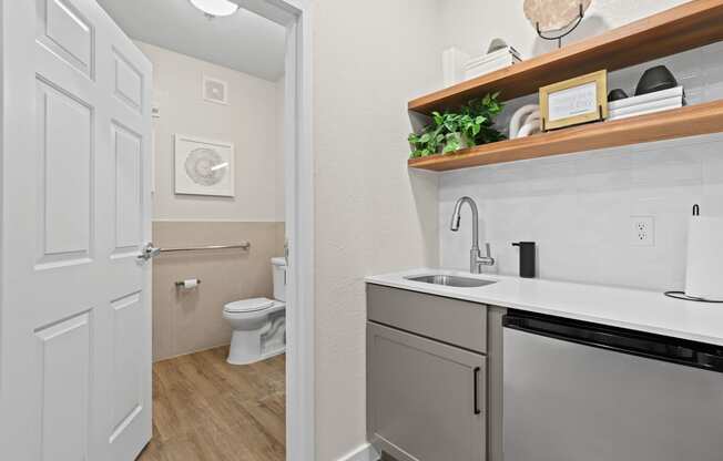 a bathroom with a sink and a toilet and a laundry room with a door open at Switchback on Platte Apartments, Littleton, CO 80120