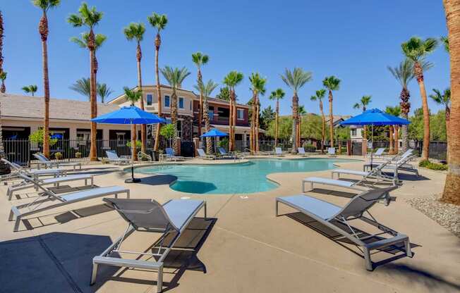 A pool surrounded by palm trees and sun loungers.