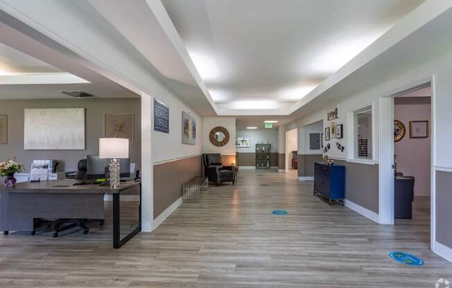A hallway with a desk and chairs on the left and a doorway on the right.
