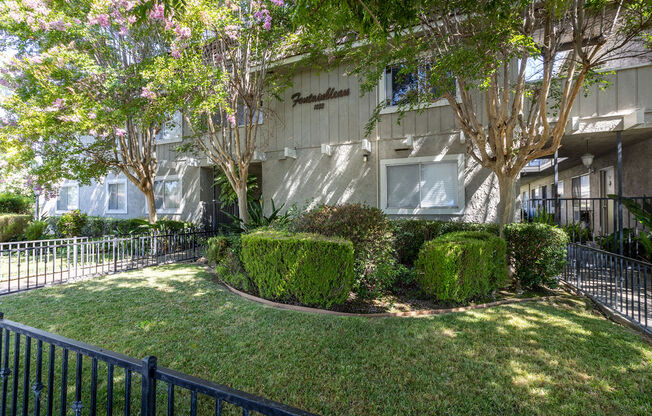 the exterior of an apartment building with a lawn and trees