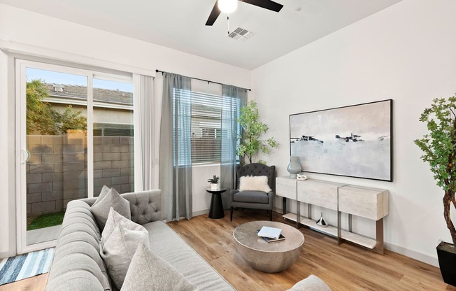 A living room with a grey couch and a painting on the wall.