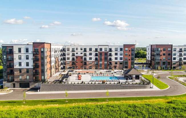 A large apartment complex with a pool in the middle of a grassy area.