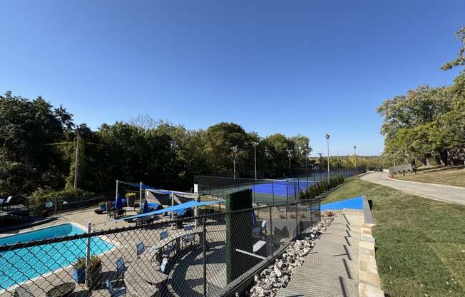 a view of a tennis court with a pool and a fence at The Boulevard, Roeland Park, KS