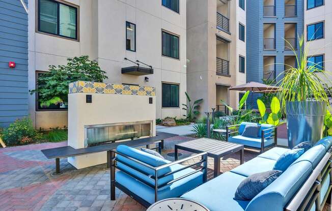 A patio with blue couches and a fireplace.