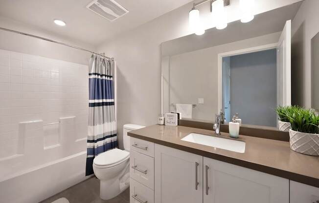 A bathroom with a toilet, sink, and mirror.