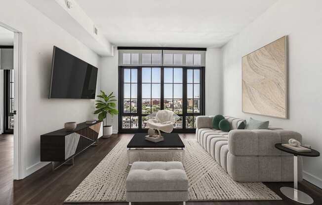 A living room with a large window, a flat screen TV, and a long couch.