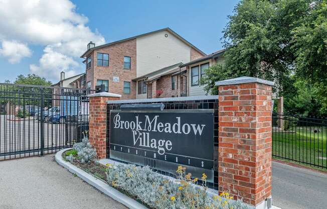 A sign that says Brook Meadow Village in front of a building.