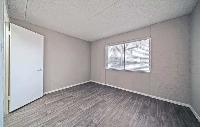 an empty living room with wood flooring and a window