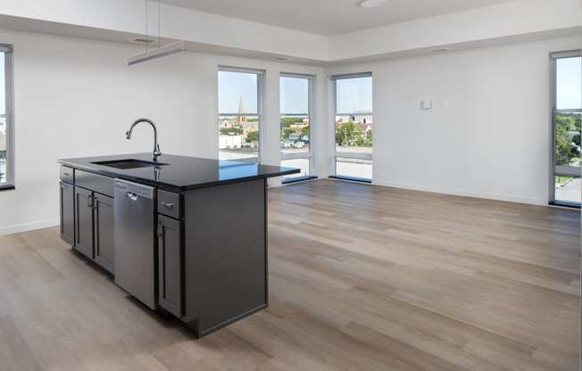 an open kitchen and living room with a large window and a black counter top at Riverhouse Apartments, Fargo, ND 58102