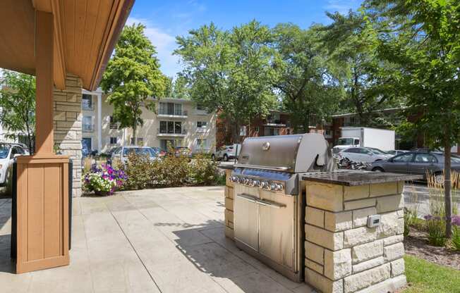 a gas grill on the side of a patio with trees