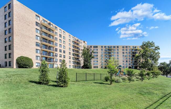 a large apartment building with a playground in a green park