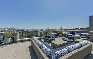 a roof top patio with blue and white furniture and a view of the ocean