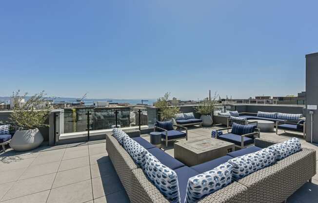 a roof top patio with blue and white furniture and a view of the ocean