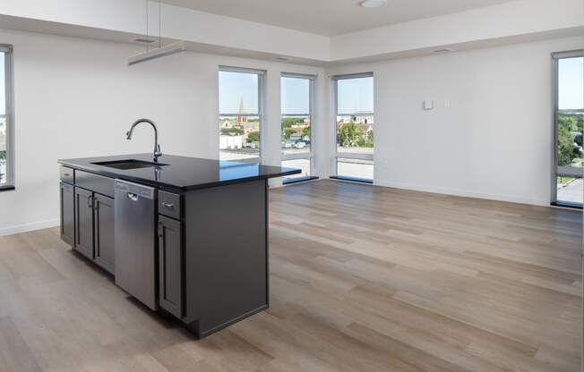 an open kitchen and living room with a large window and a black counter top at Riverhouse Apartments, Fargo, North Dakota