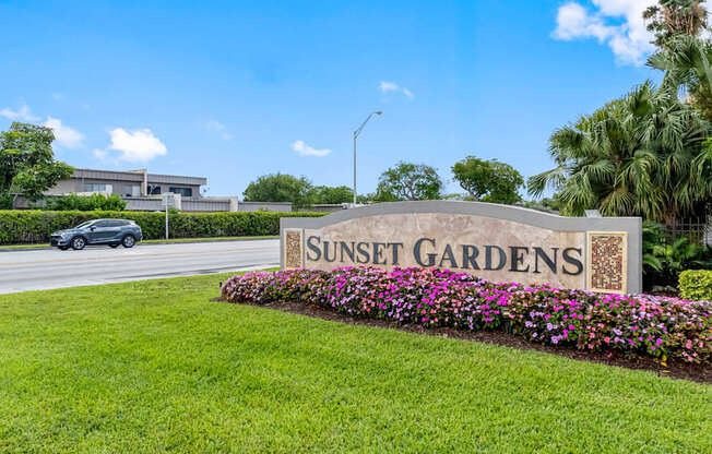 A sign that says Sunset Gardens in front of a building.