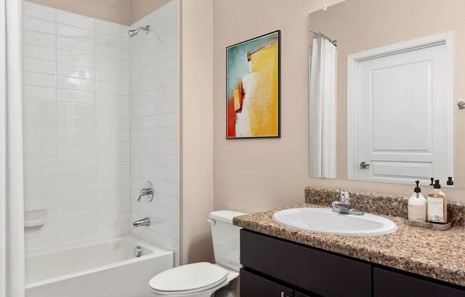 A bathroom with a white toilet, a sink, and a painting on the wall.