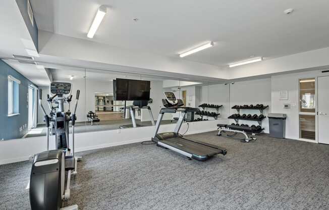 a gym with exercise equipment and mirrors in a building