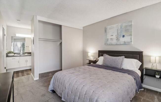 A bedroom with a bed, nightstand, and a painting on the wall.