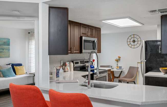 a kitchen and living room with orange chairs and a white counter top