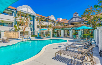 a swimming pool with lounge chairs and umbrellas