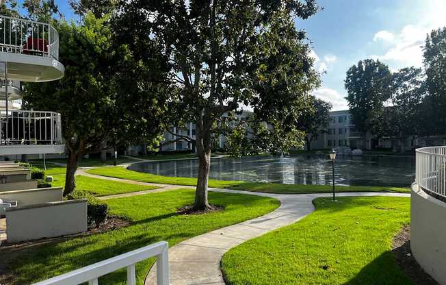 A tree in a grassy area with a white fence in the foreground.