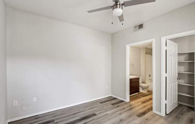 A room with a ceiling fan and a wooden floor.