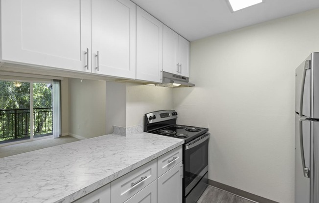 kitchen with efficient appliances, plank flooring, and white cabinetry at Casa Blanca Apartment Homes, Everett, WA