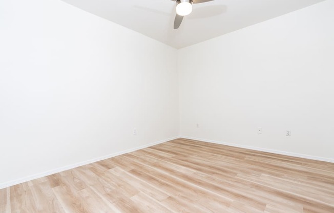 an empty room with wooden floors and a ceiling fan